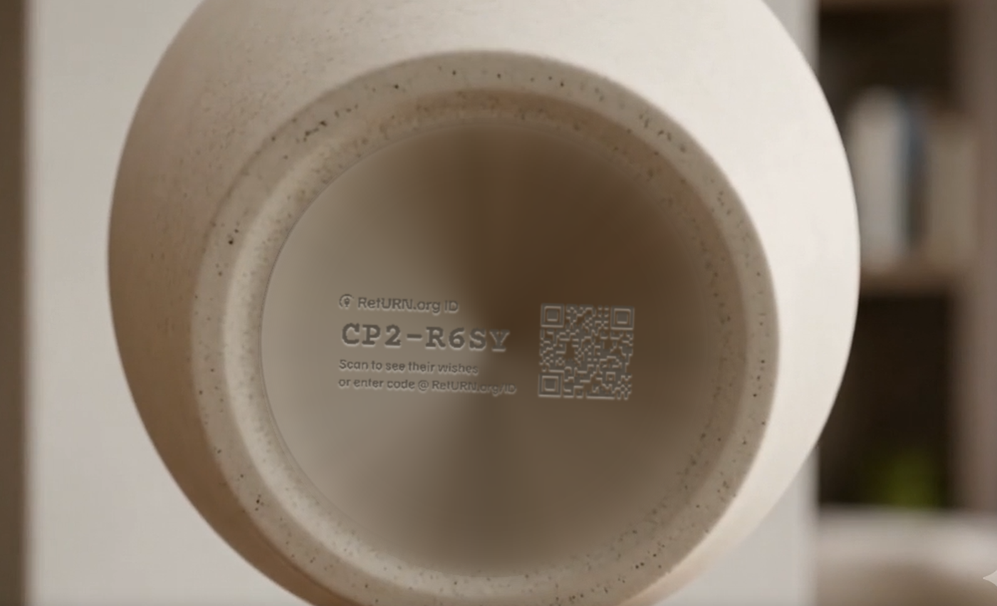 The base of a ceramic urn with a RetURN.org ID cut into the surface: the code CP2-R6SY, the instruction line, and a QR code, engraved rather than applied as a label.